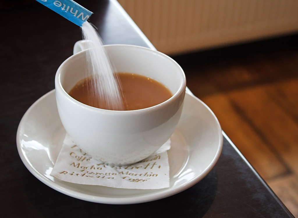 pouring sugar into coffee mug