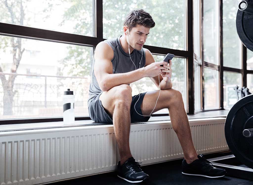 Man holding phone wearing workout clothes at gym