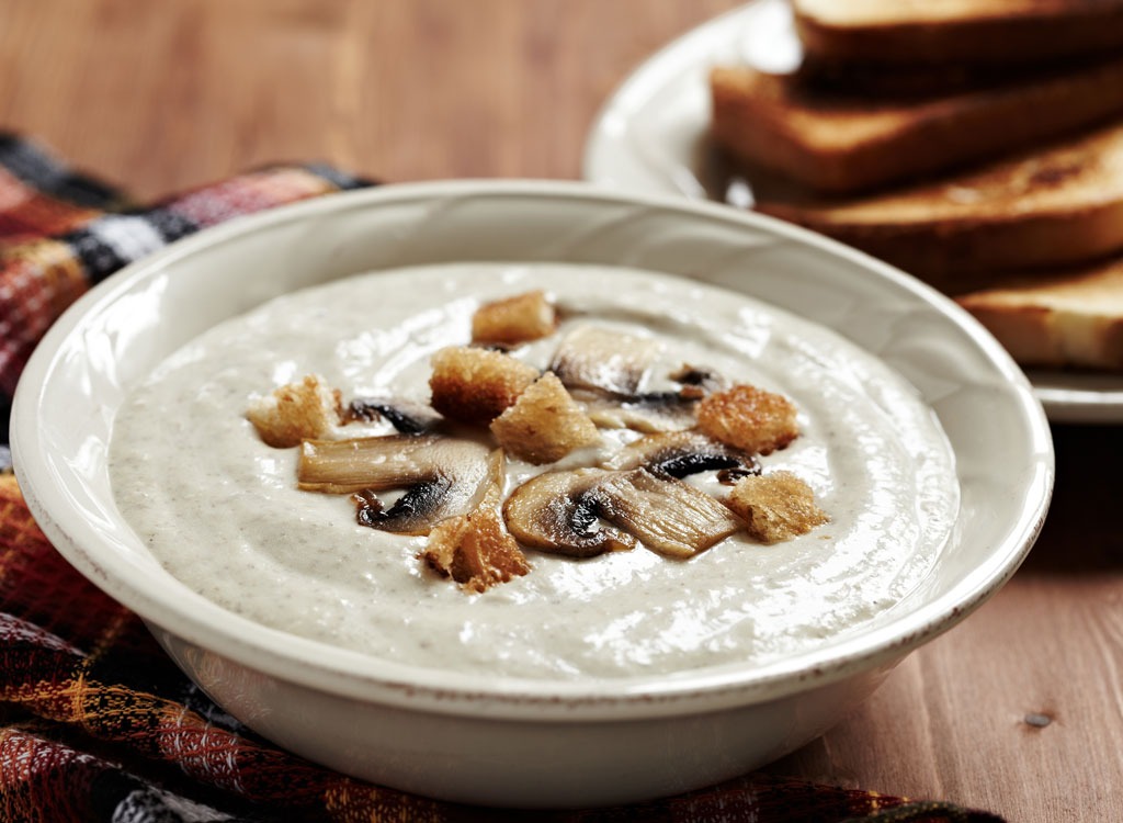 Cream based soup with mushrooms in white bowl