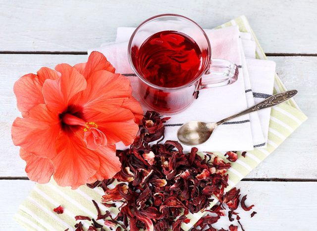 cup of hibiscus tea with hibiscus flower and petals