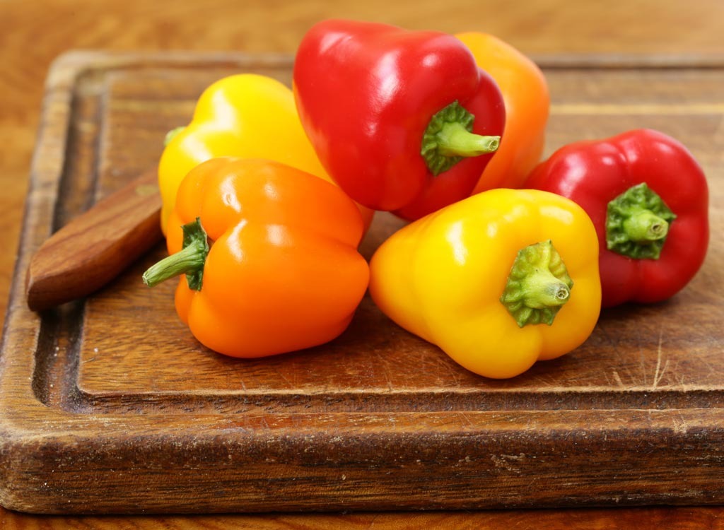 orange yellow and red bell peppers on wood cutting board
