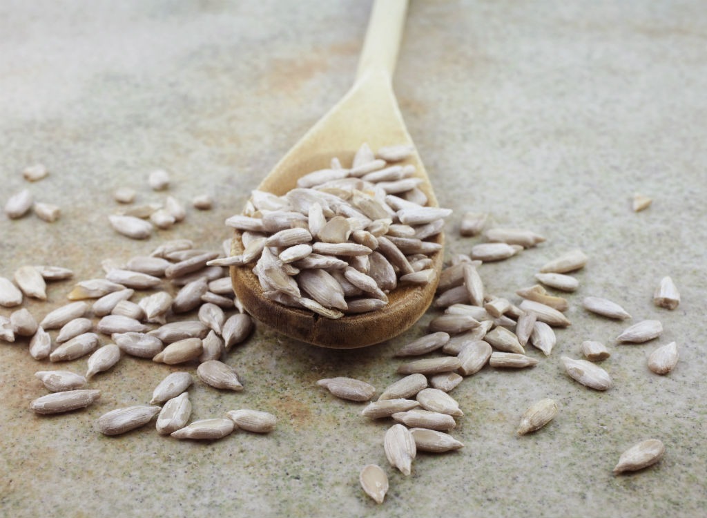 Sunflower seeds in a wooden spoon on a gray background