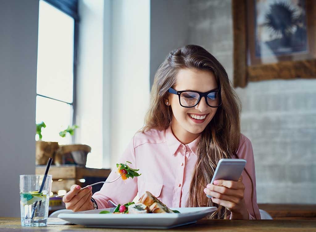 woman eating while using phone