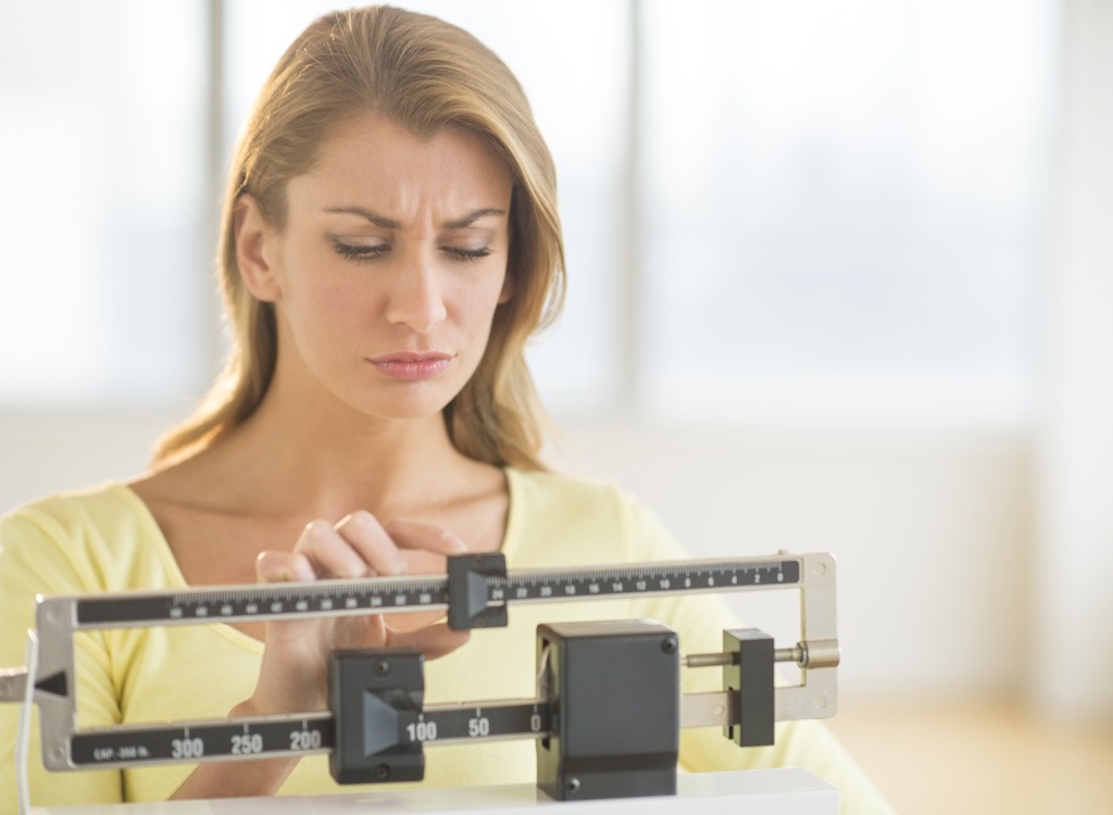 Frowning woman standing on scale