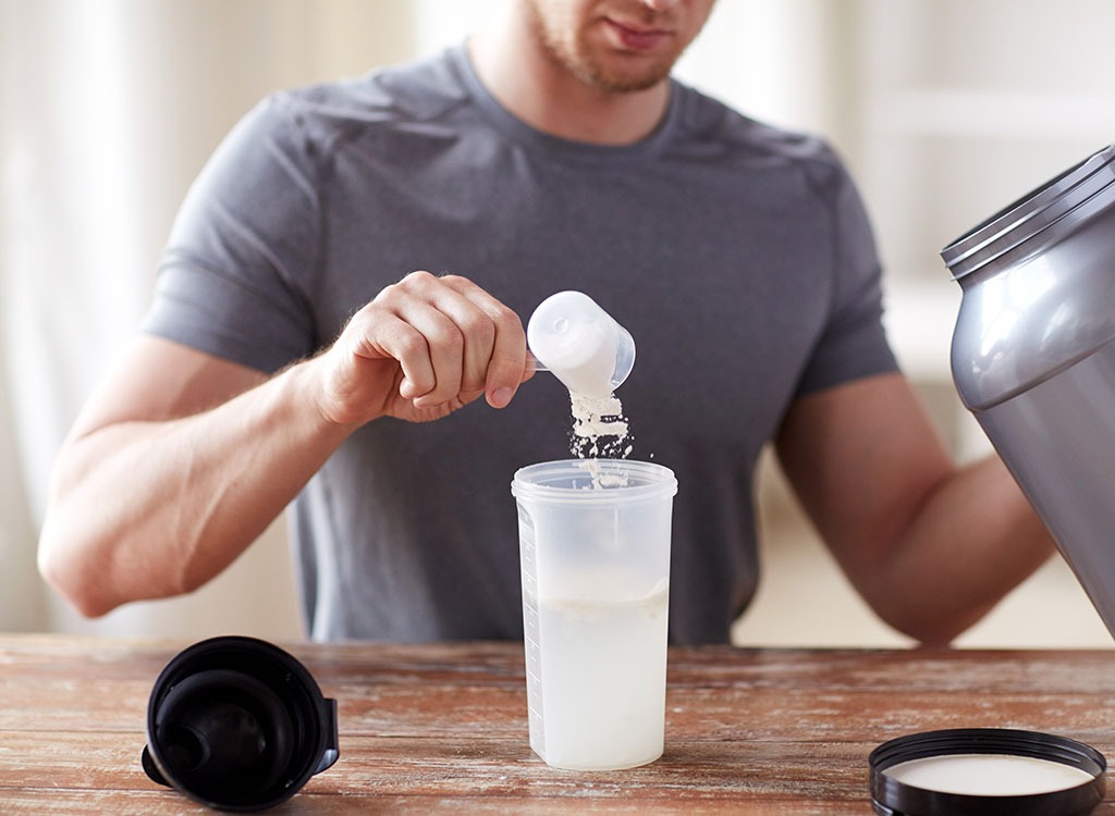 Man pouring protein powder in blender bottle