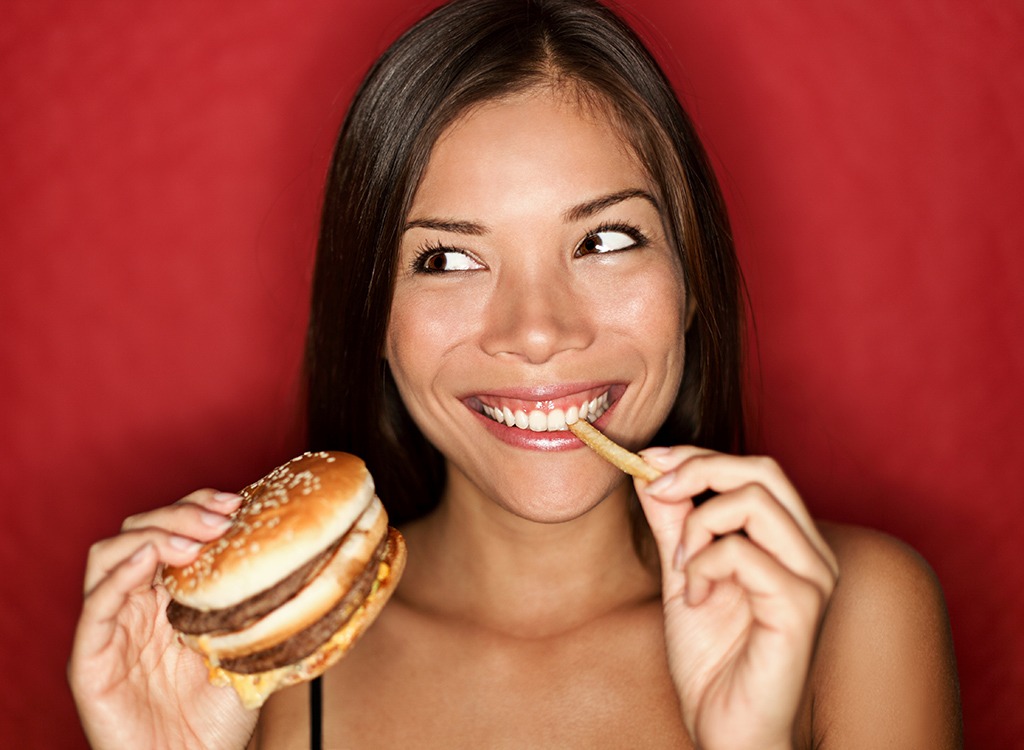 Woman eating a burger and fries - best cheat meal on cheat day