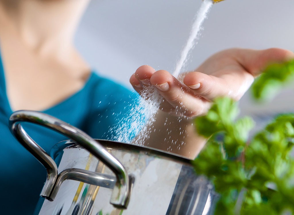 woman salting water 8 cooking mistakes making you fat