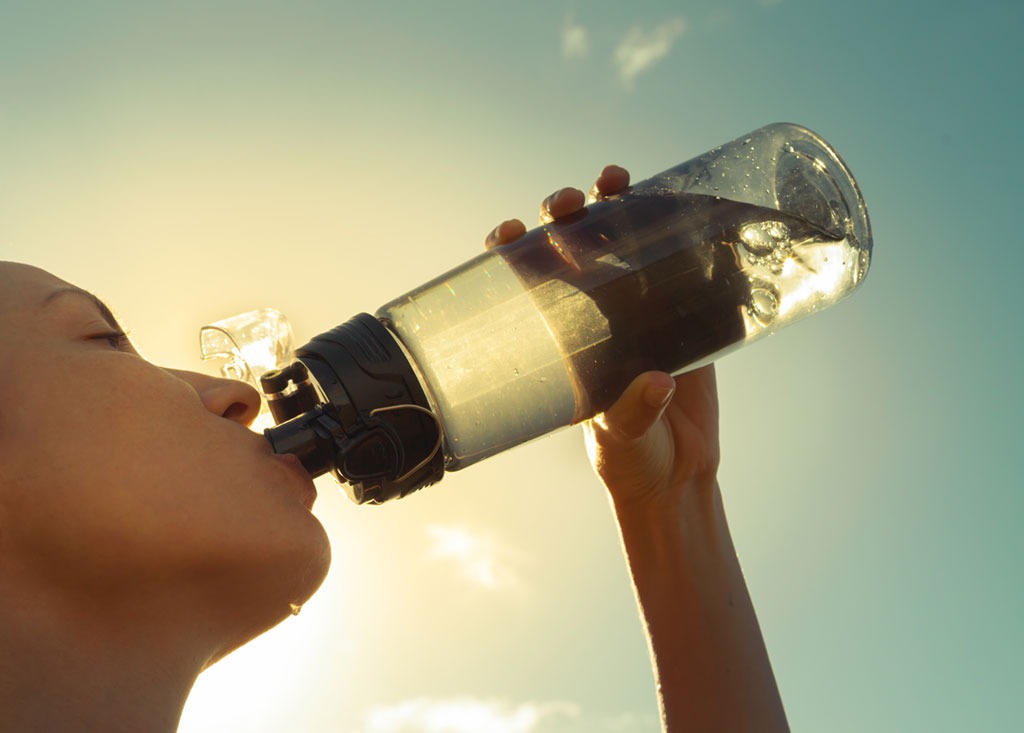 woman drinking out of water bottle