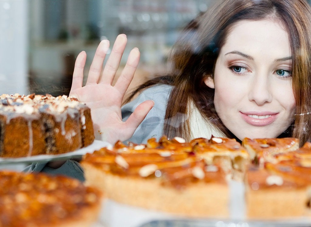 Woman staring at pastries in a case with food cravings