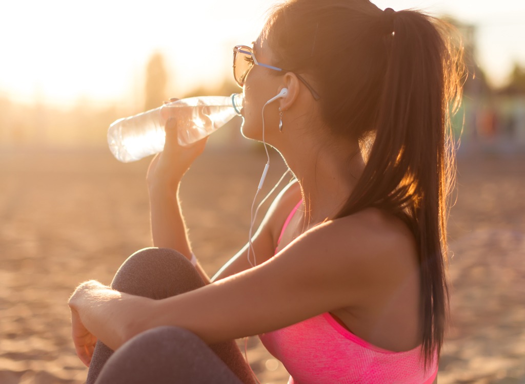 woman drinking water from plastic bottle