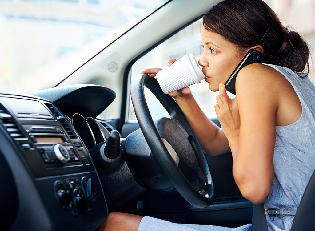Busy woman driving car and drinking coffee