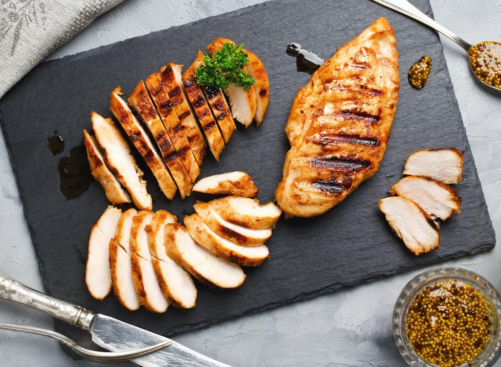 Cut up cooked chicken breast on a dark grey cutting board