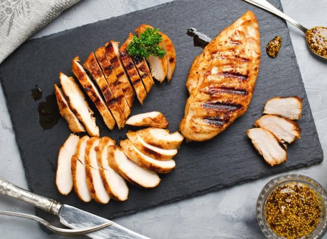 Cut up cooked chicken breast on a dark grey cutting board