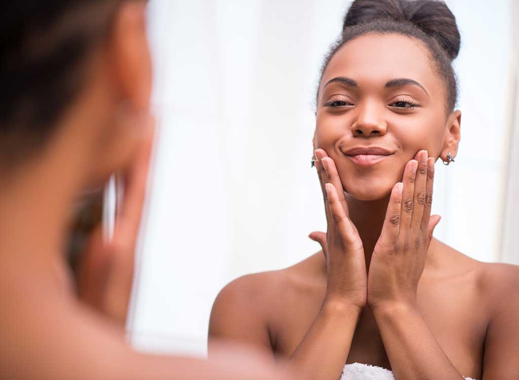 Woman touching face in mirror