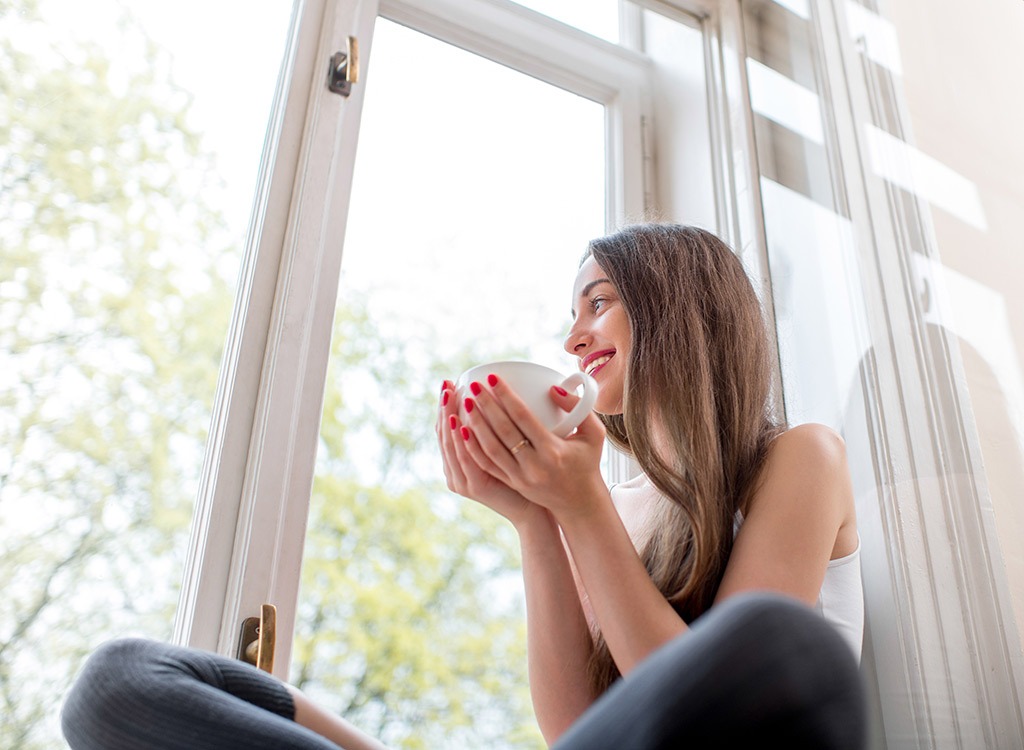 girl drinking tea by window