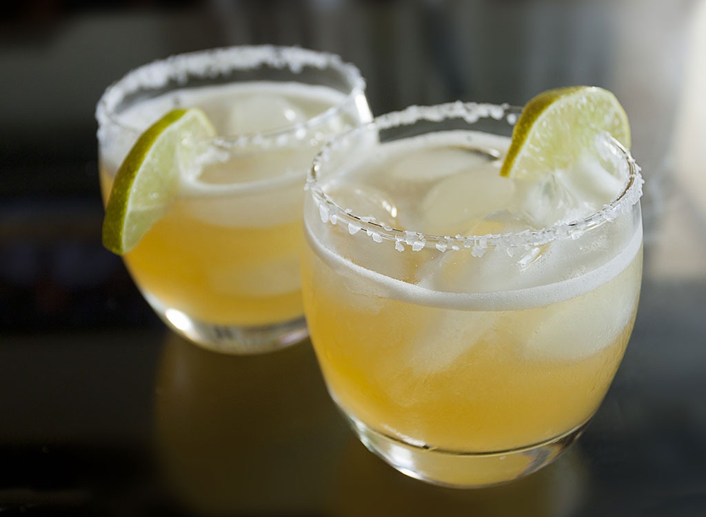 two margaritas in glasses with lime wedges