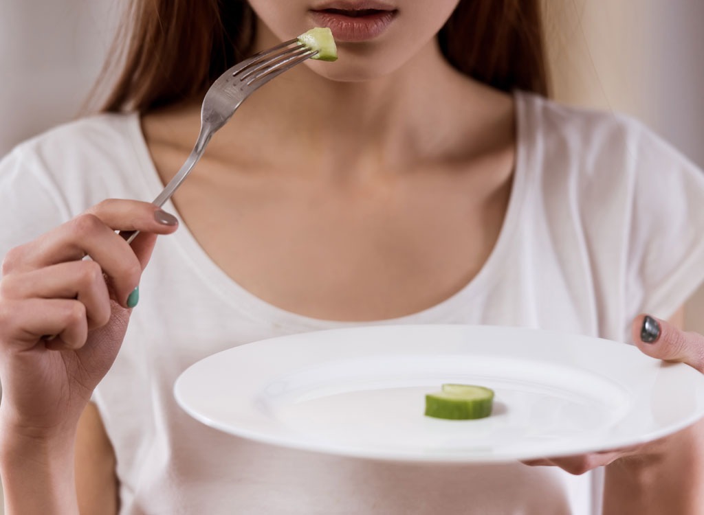 Woman barely eating cucumber