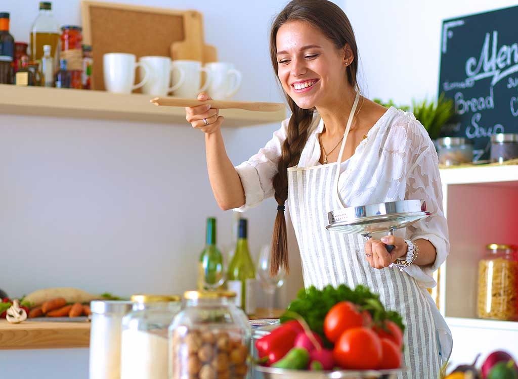 Woman tasting food while cooking in kitchen
