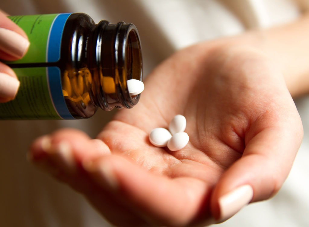 Woman pouring pills into hand