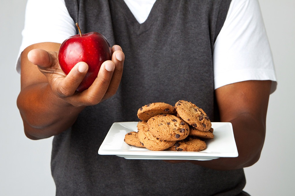 Man holding a plate of cookies and an apple