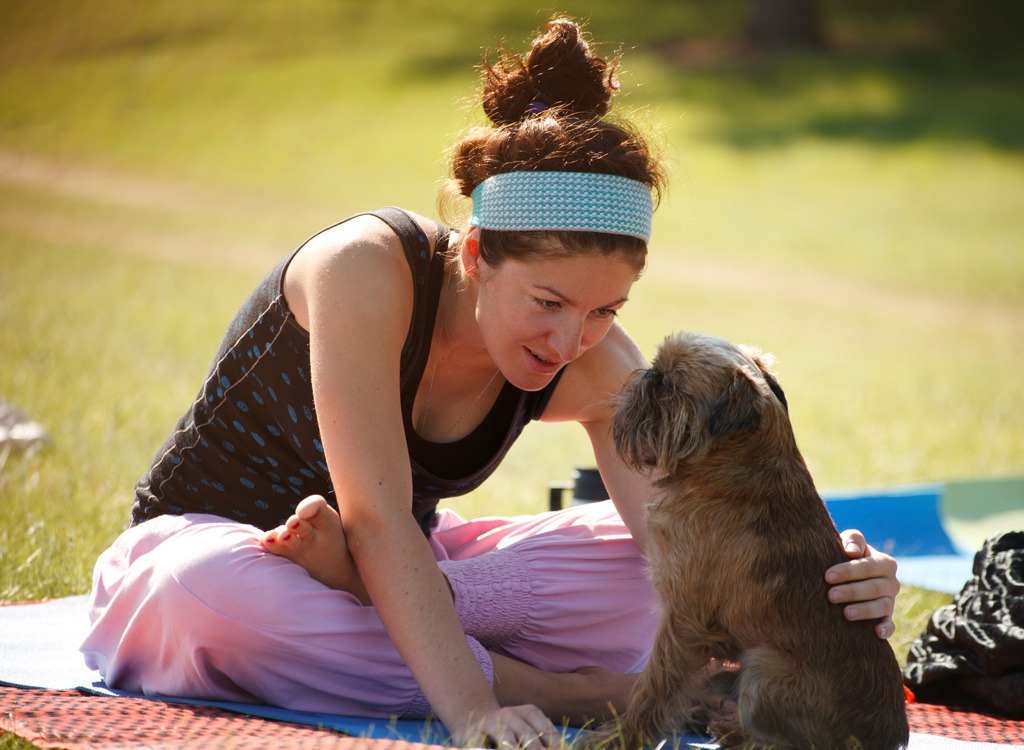 Woman doing yoga with dog in park